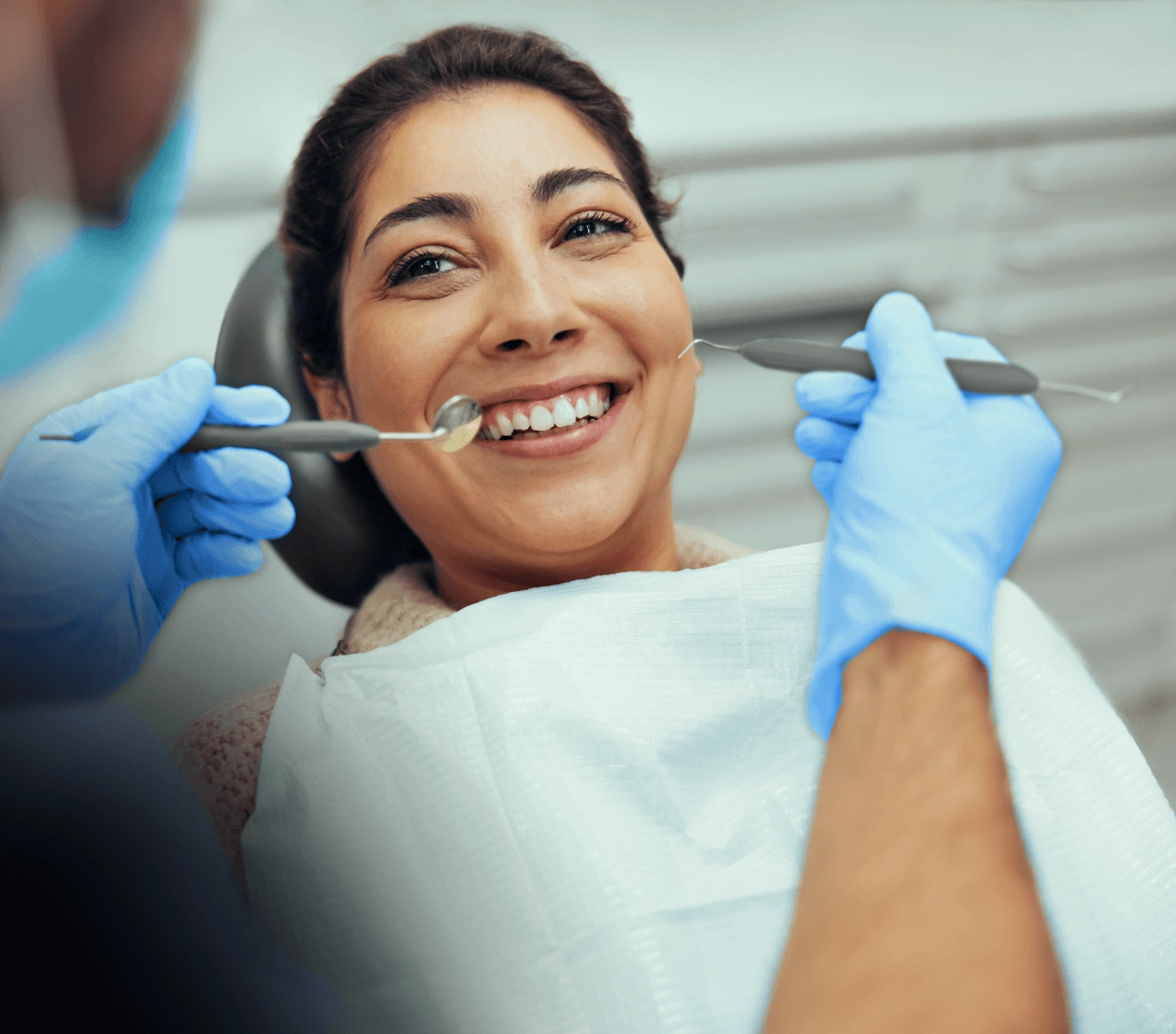 Patiente assise dans une chaise de dentiste avec dentiste utilisant un miroir et un détartreur dentaire